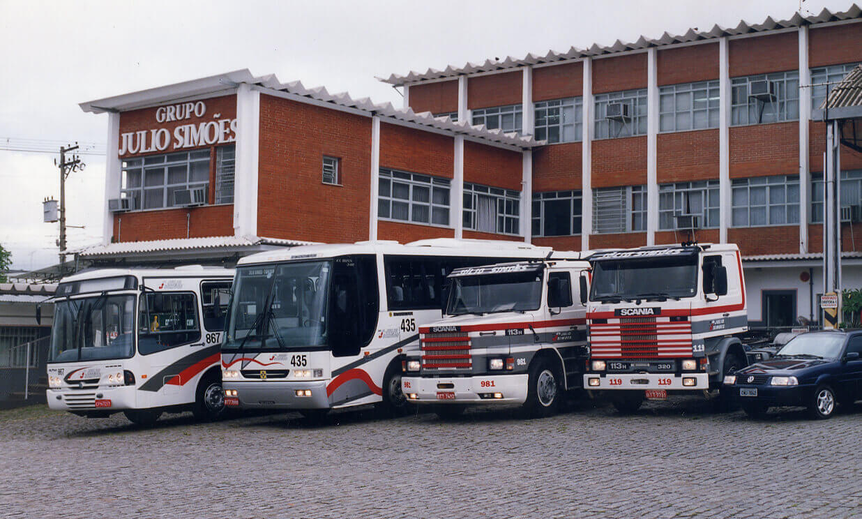 Veículos variados estacionados em frente a um prédio em foto dos anos 90